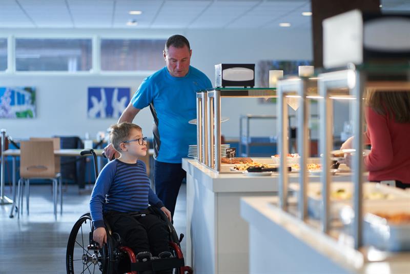 boy in a wheelchair with his father at the breakfast buffet in Hotell fritidsparken