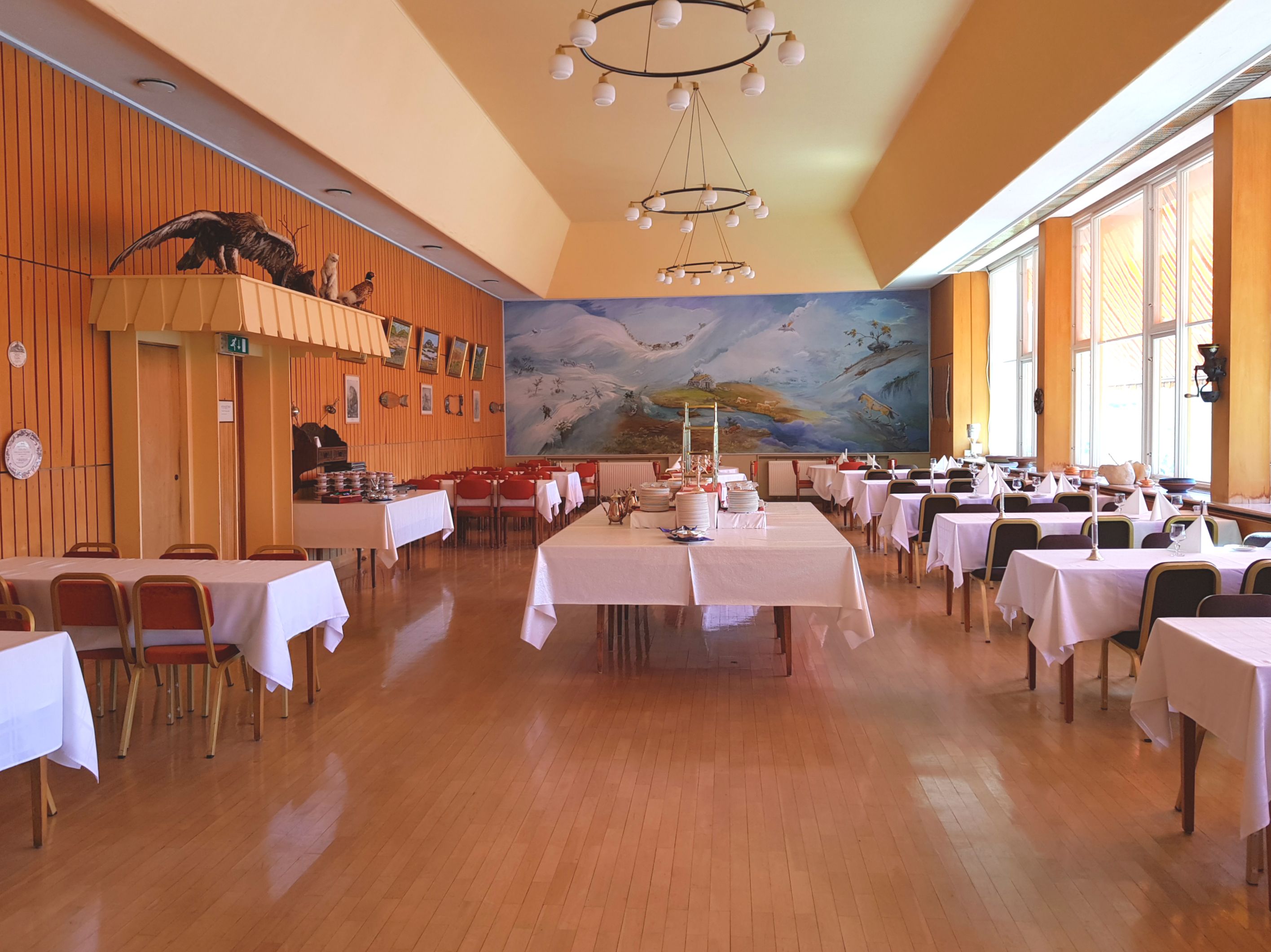 Spisesalen på hotellet, med et stort, blått veggmaleri i bakgrunnen.