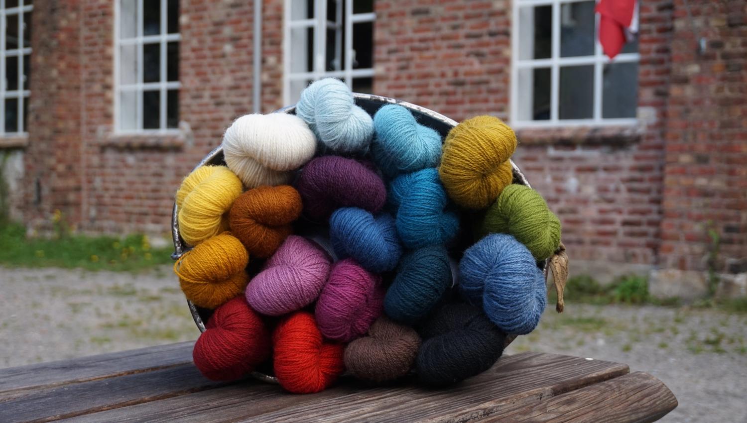 Bucket of yarn in various colors: red, burgundy, brown, dark blue, blue, light blue, yellow, orange, mustard yellow, white, purple, pink.