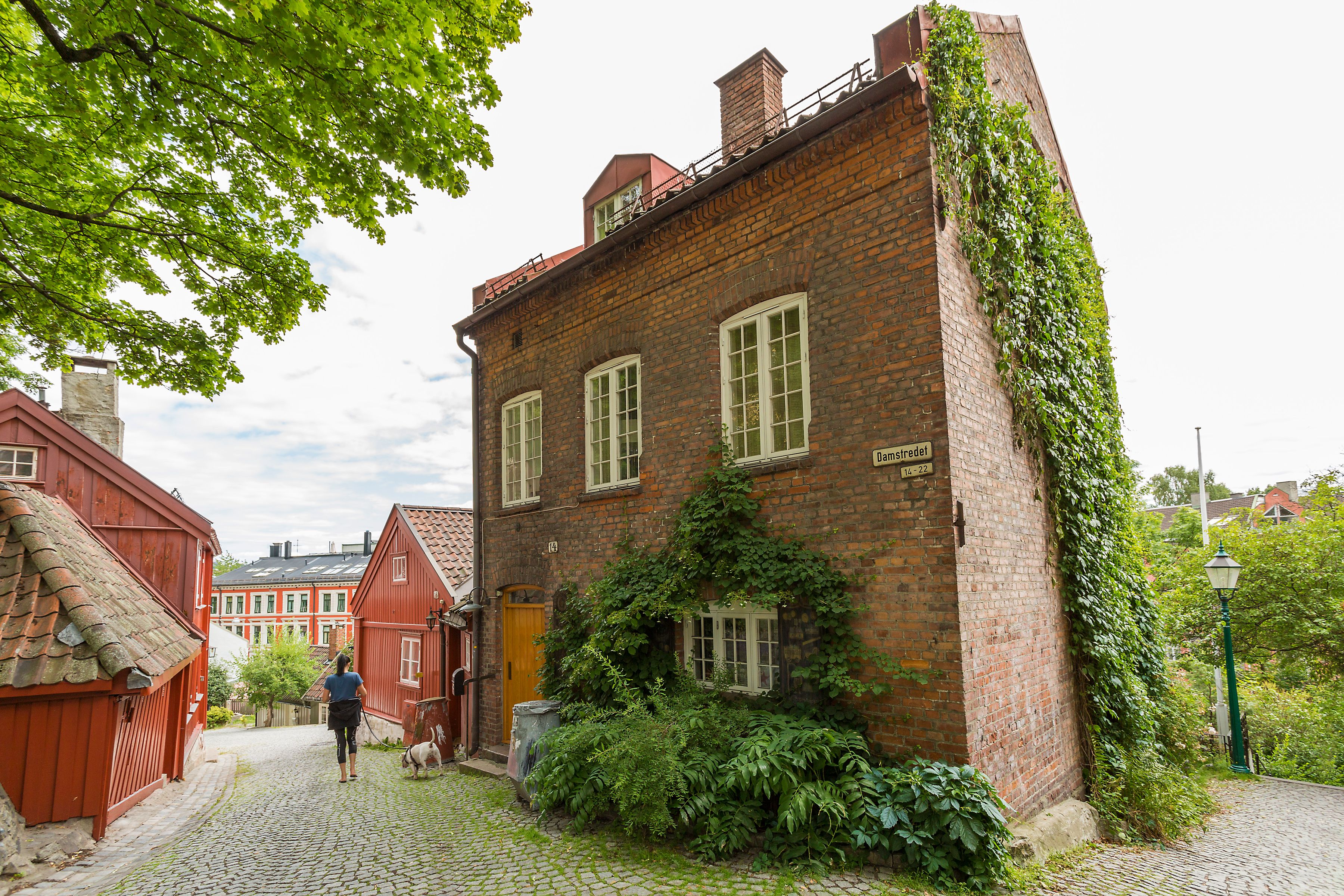 Mursteinshus øverst i telthusbakken med klatreplante langs veggen.