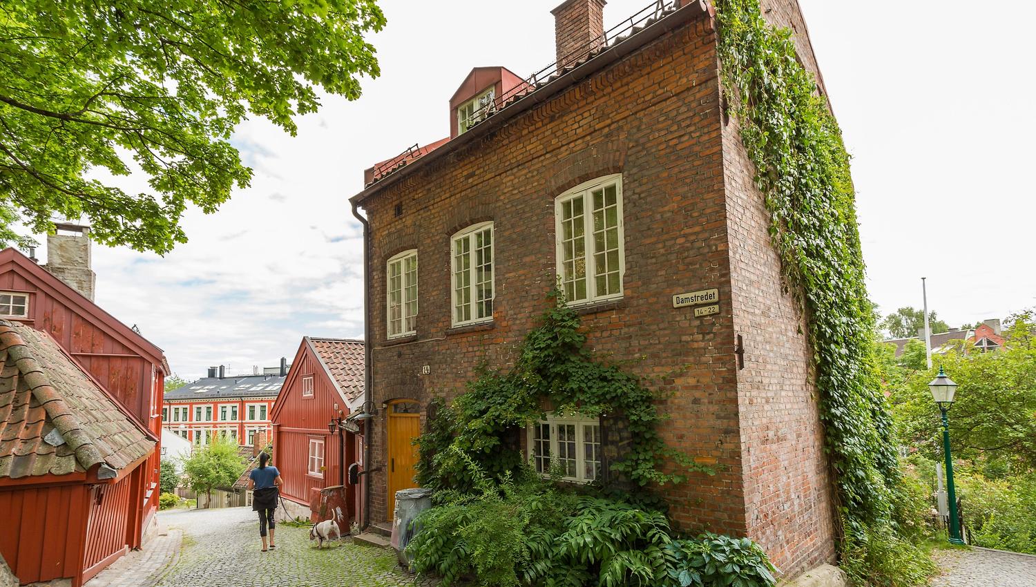 Mursteinshus øverst i telthusbakken med klatreplante langs veggen.