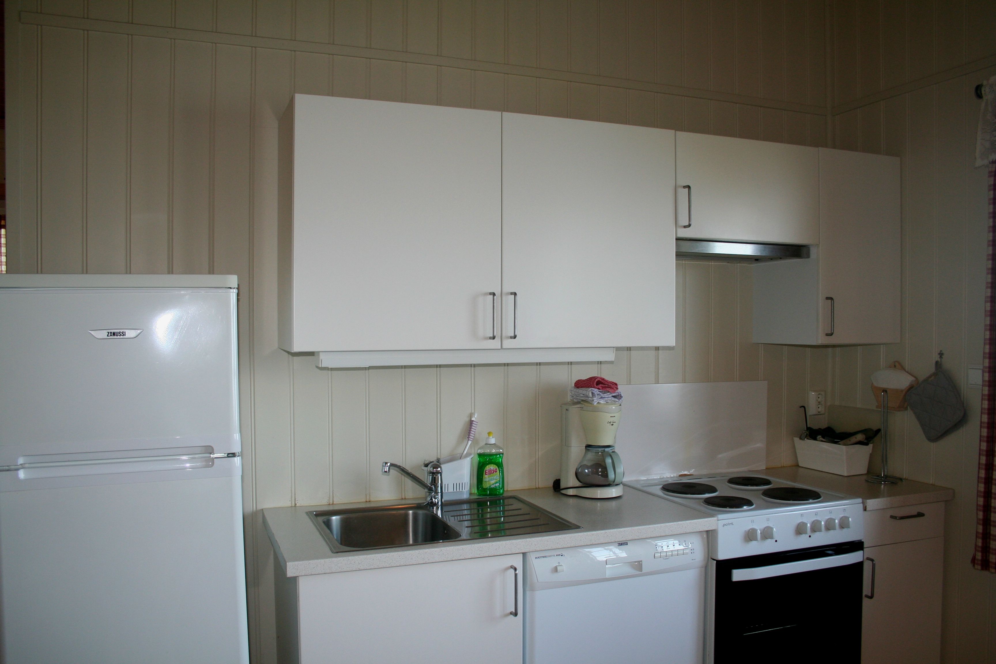 Moderne kjøkkenkrok i hytte på Oddland Camping med komfyr, kjøleskap og kaffitraktar.