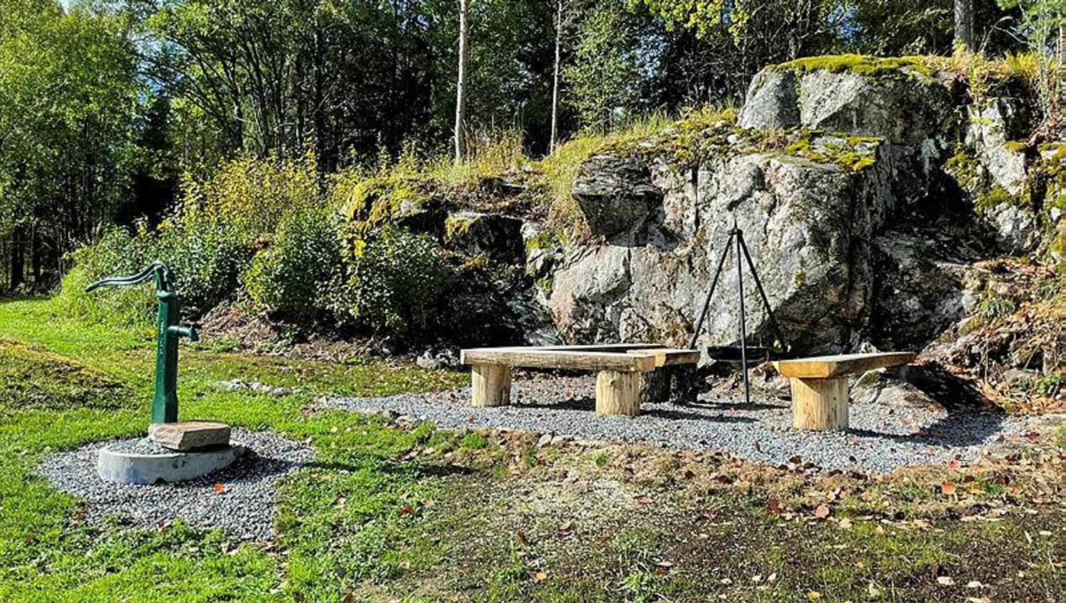 uteområde med benker, bålpanne og brønn