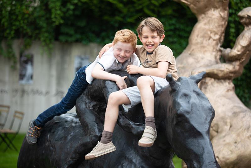 Two children playing on a horse statue