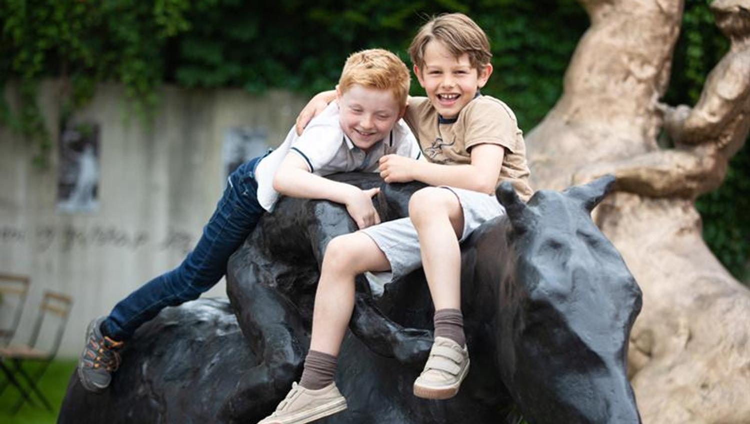 Two children playing on a horse statue