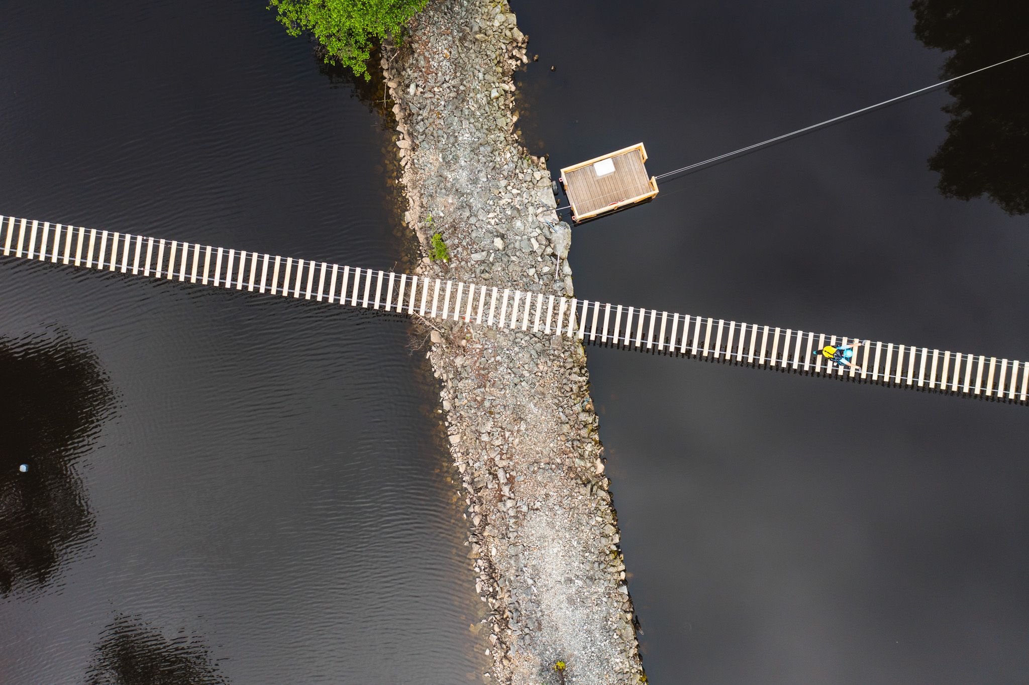 En person som krysser hengebroa, bildet er tatt fra lufta.