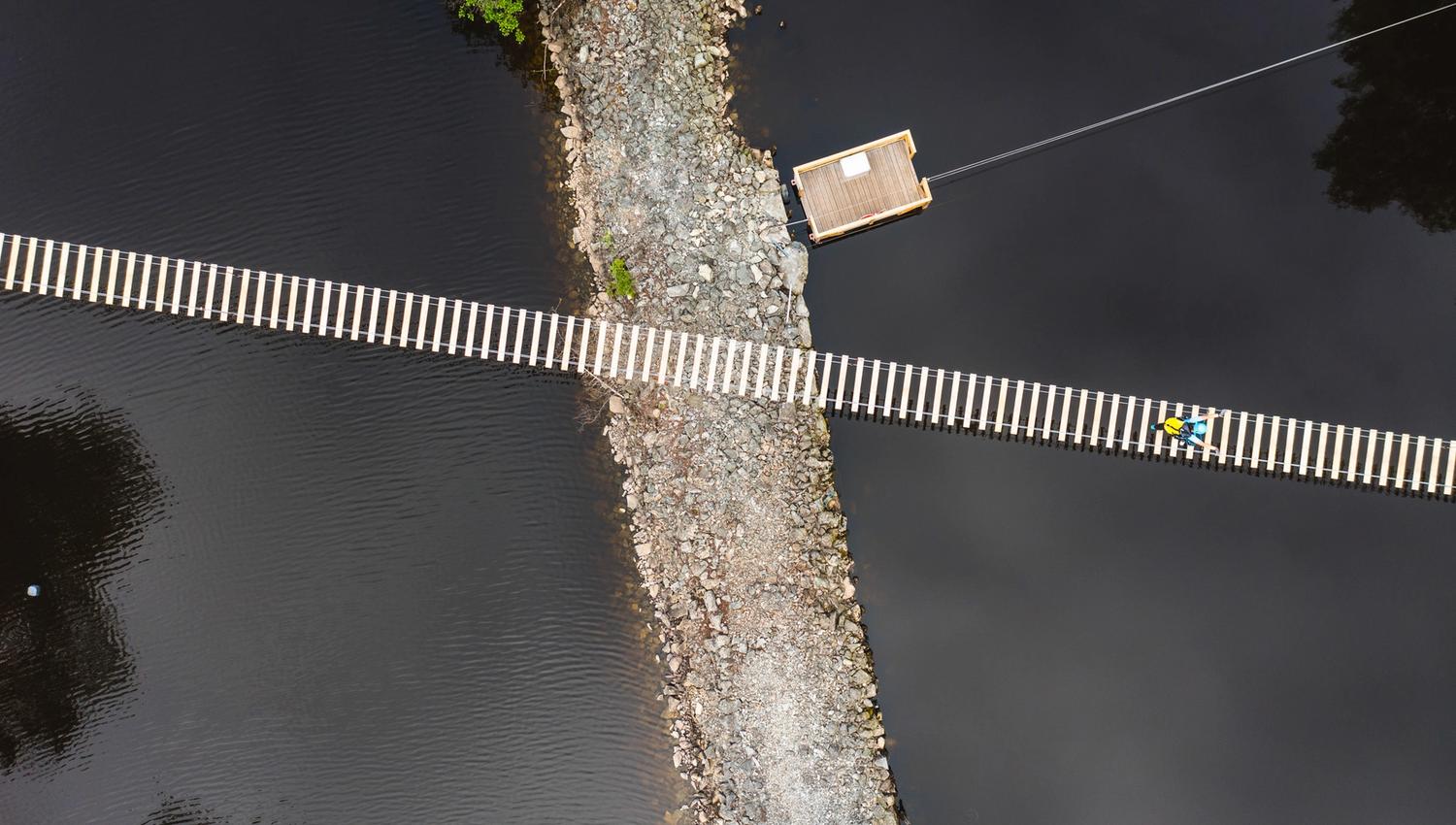 En person som krysser hengebroa, bildet er tatt fra lufta.