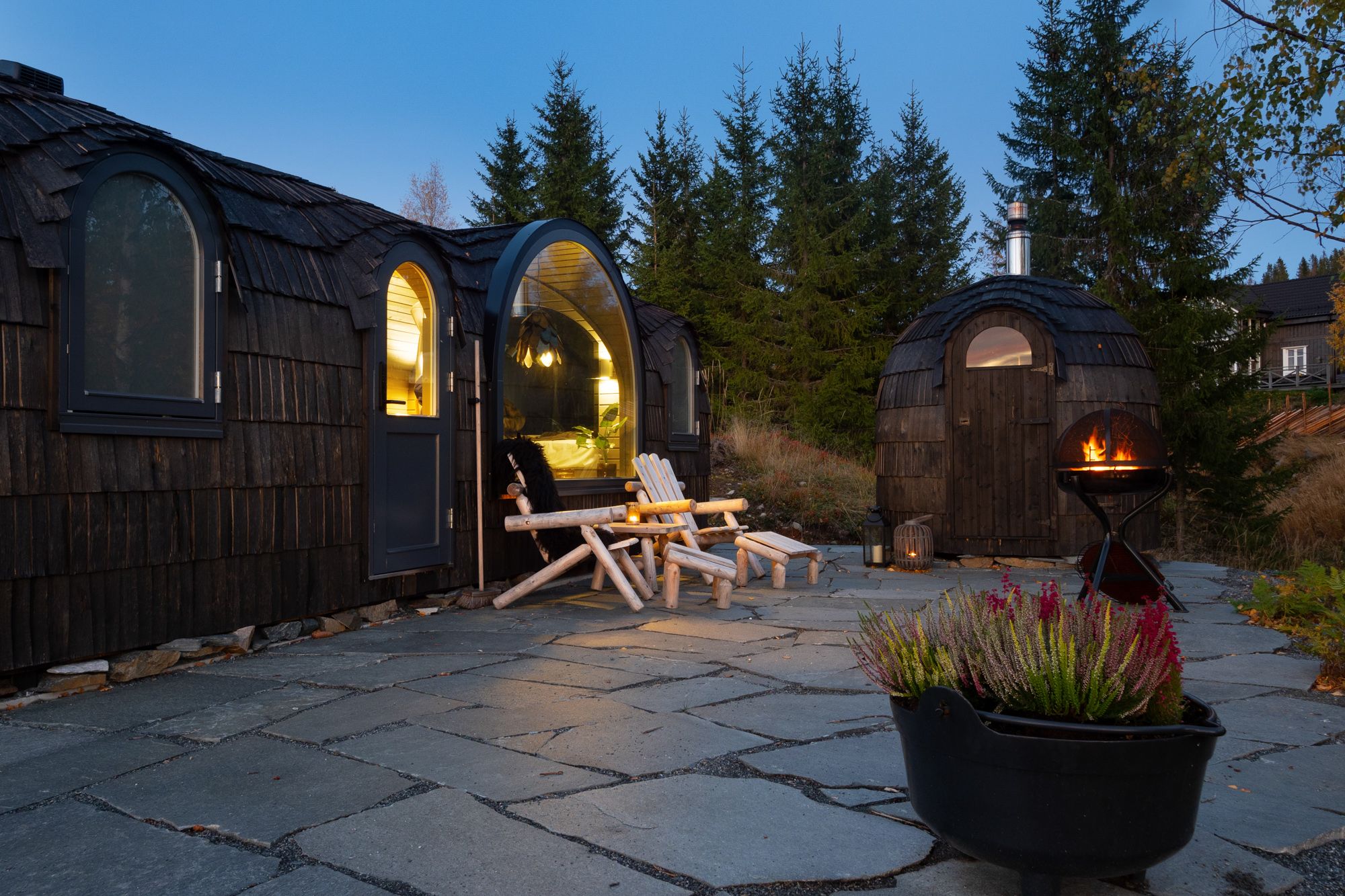 2 små hytter med stoler foran og fyr i en stående grill