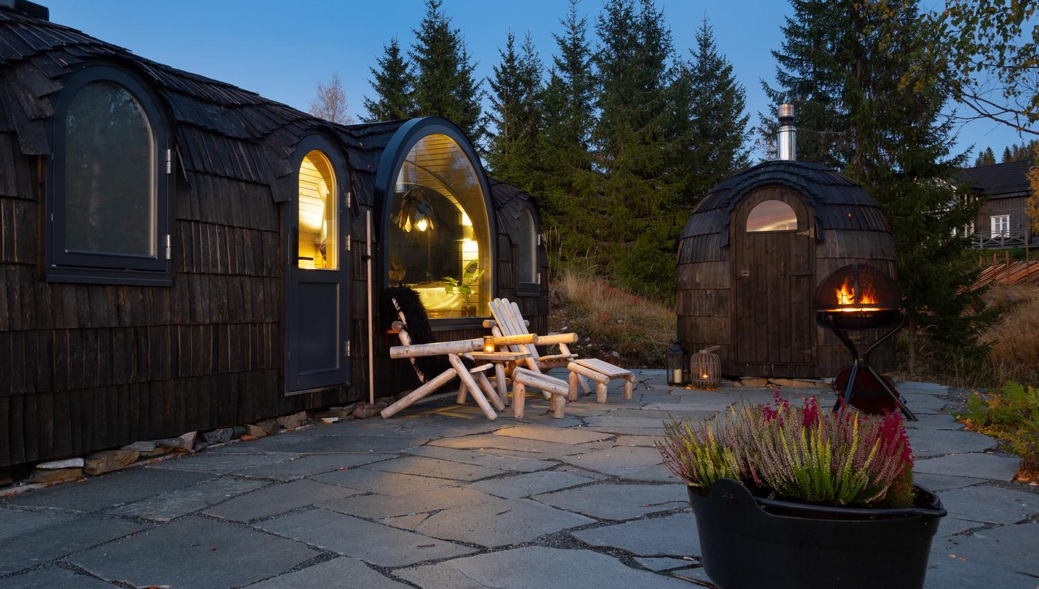 2 små hytter med stoler foran og fyr i en stående grill