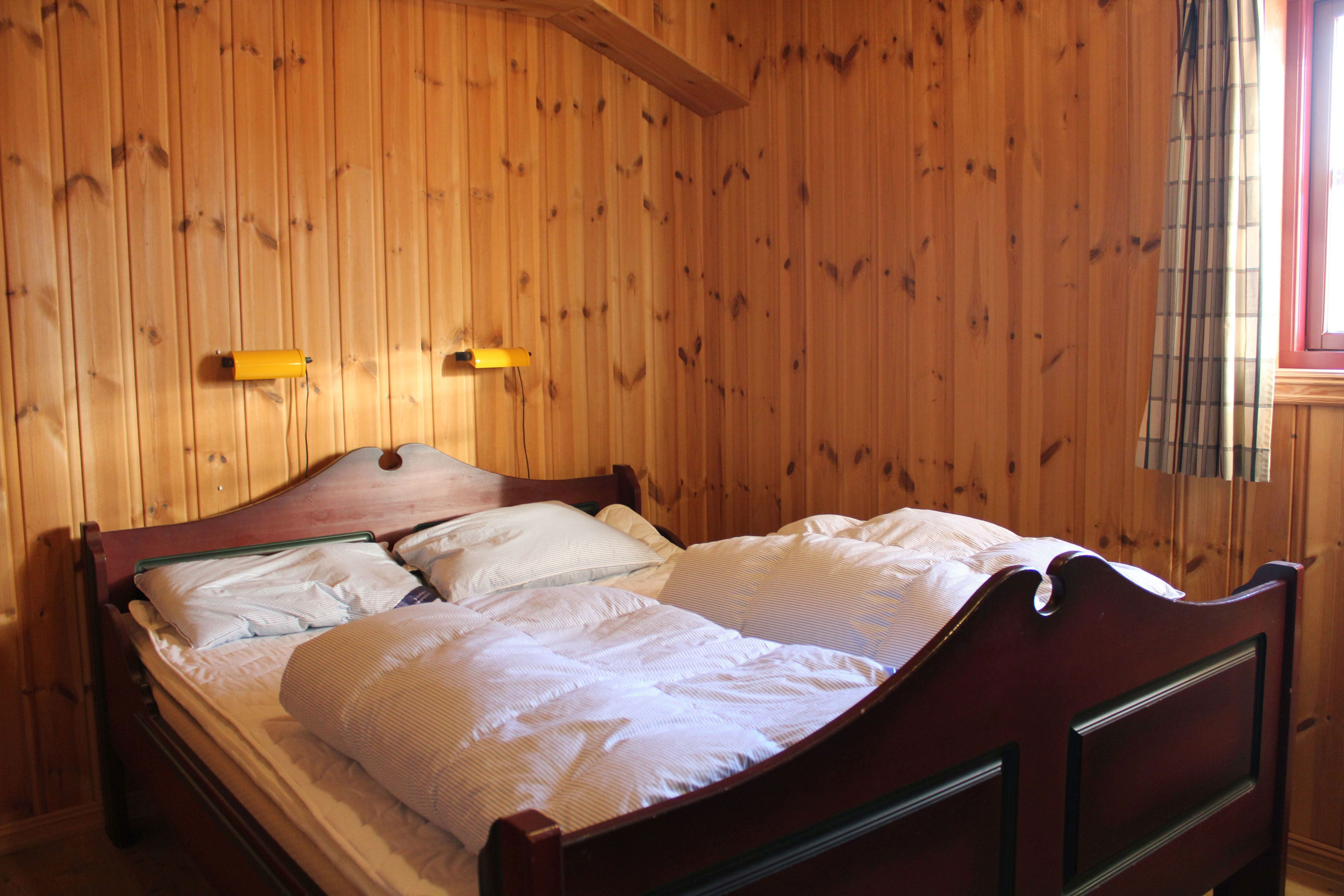 A bed with pillows and a wall with wooden panels.
