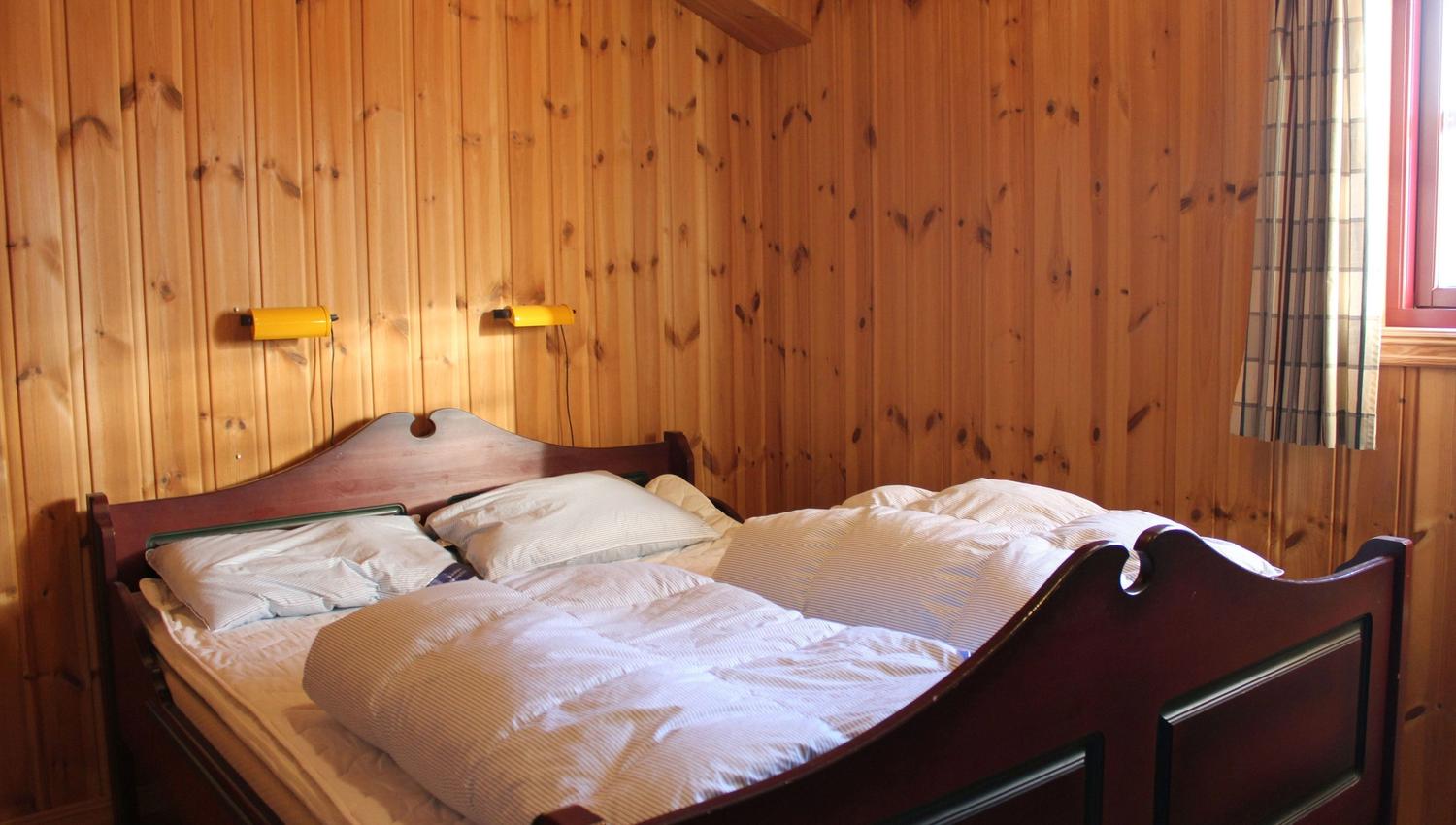 A bed with pillows and a wall with wooden panels.