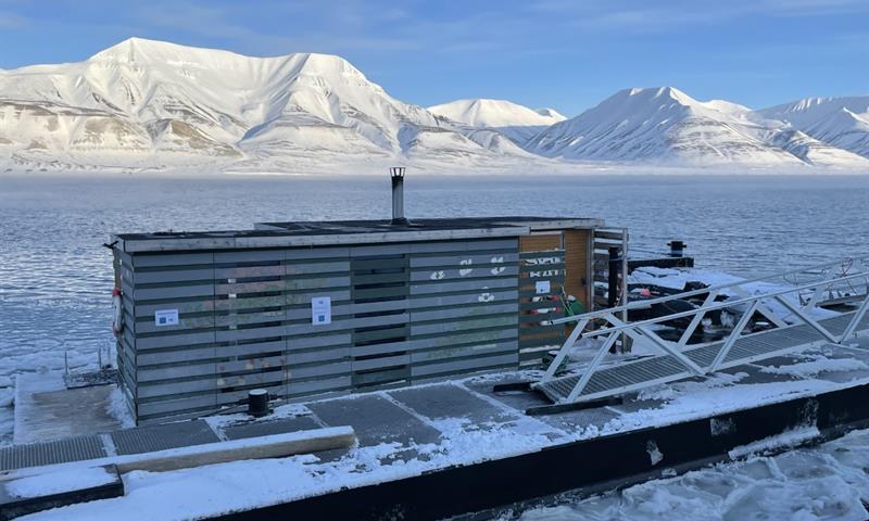 Badstuen SvalBad i Longyearbyens havn med snødekte fjell og en fjord med drivis i bakgrunnen