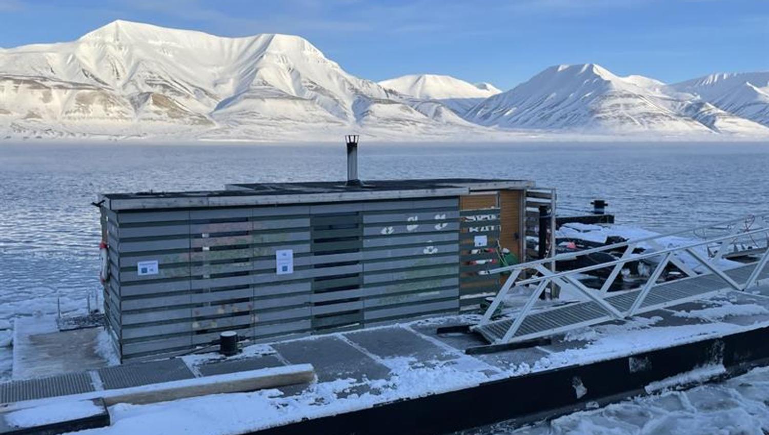 Badstuen SvalBad i Longyearbyens havn med snødekte fjell og en fjord med drivis i bakgrunnen