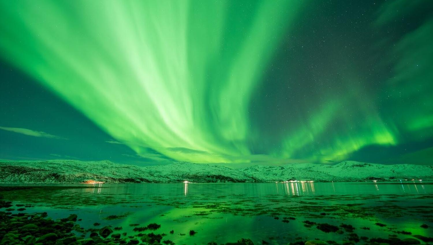Nordlyset flyr over fjorden