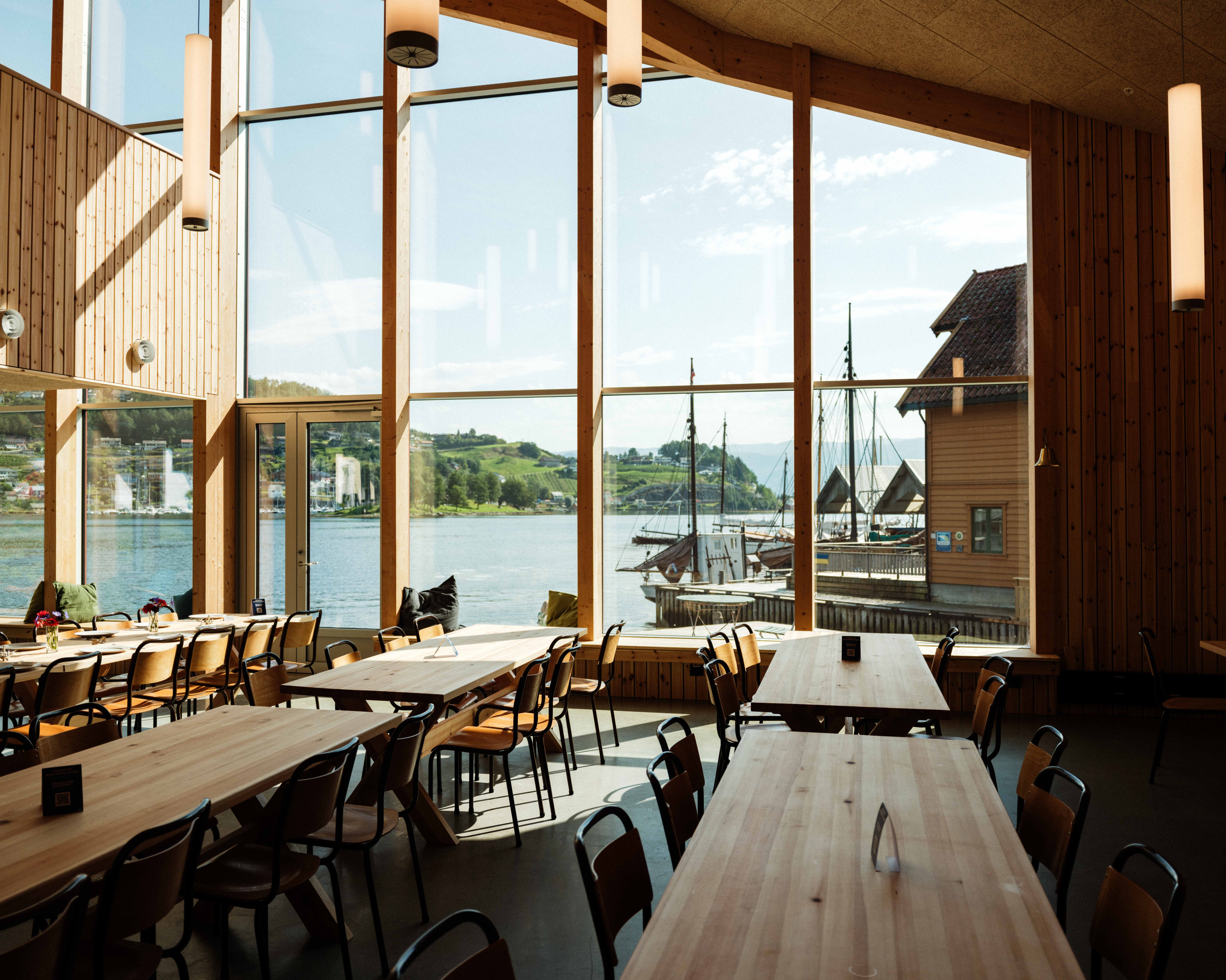 Bright and spacious interior at the Hardanger Maritime Centre, with panoramic views of the fjord and traditional wooden boats.