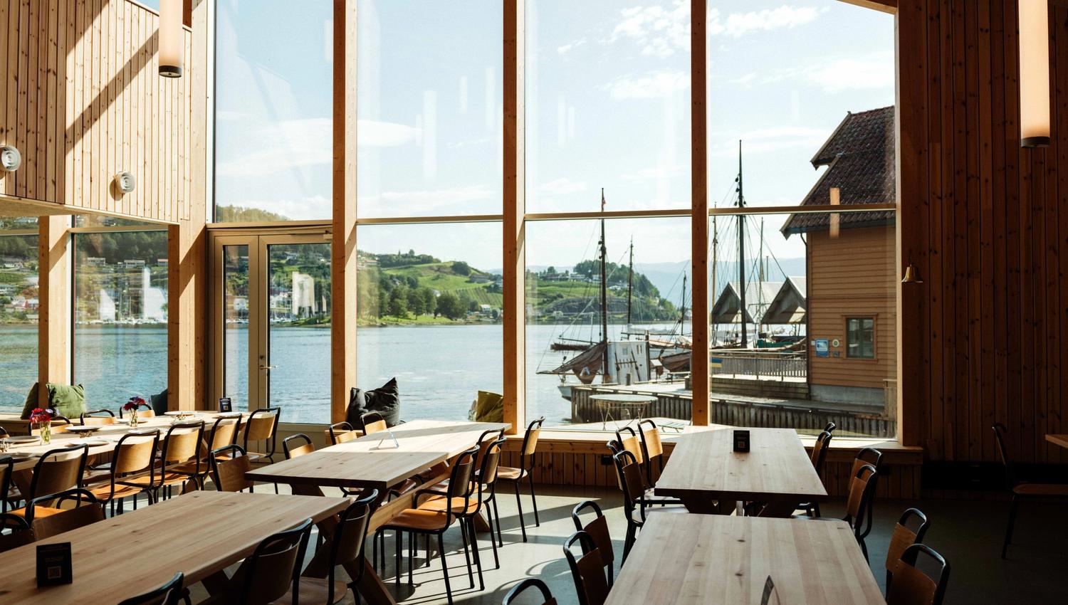 Bright and spacious interior at the Hardanger Maritime Centre, with panoramic views of the fjord and traditional wooden boats.