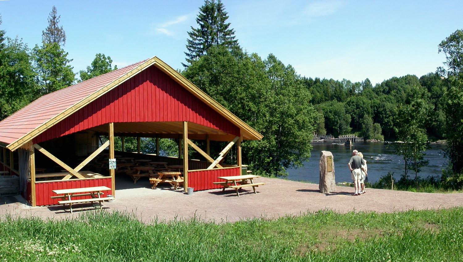 Et rødt stolpehus ved fossen