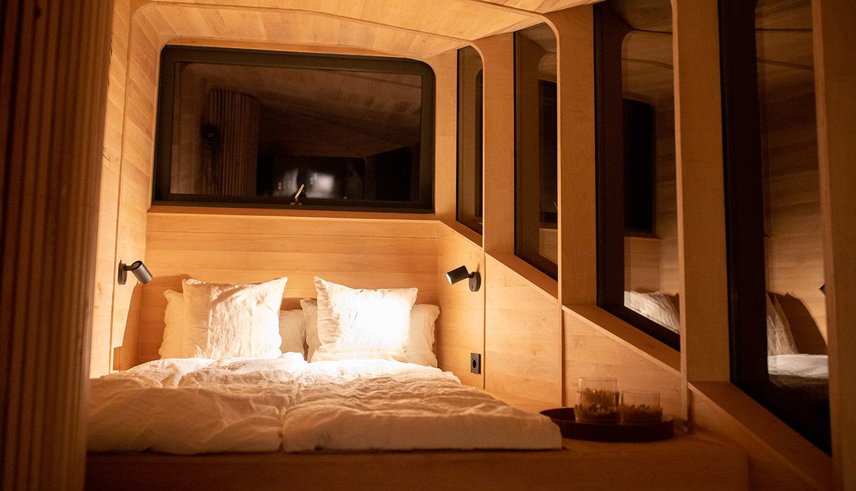 Ei stemningsfull natt i Woodnest tretopphytte – varme treflater og ein innbydande seng.