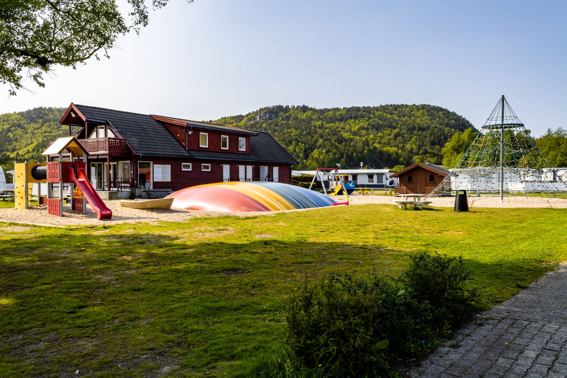 Solstrand Camping playground. A climbing tower in the center and a colorful jumping pillow beside it.