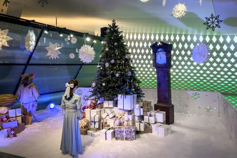 Utstilling med juletre, bestefarsklokke, julegaver og dukker