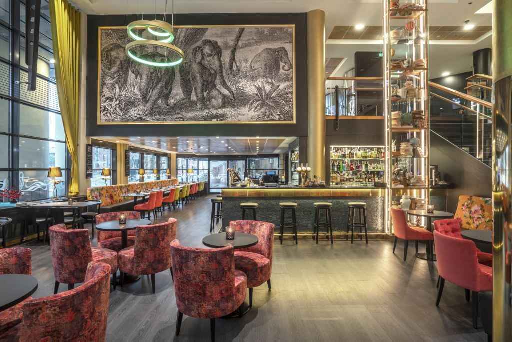 Glamorous hotel bar with a mural on the wall and golden details.