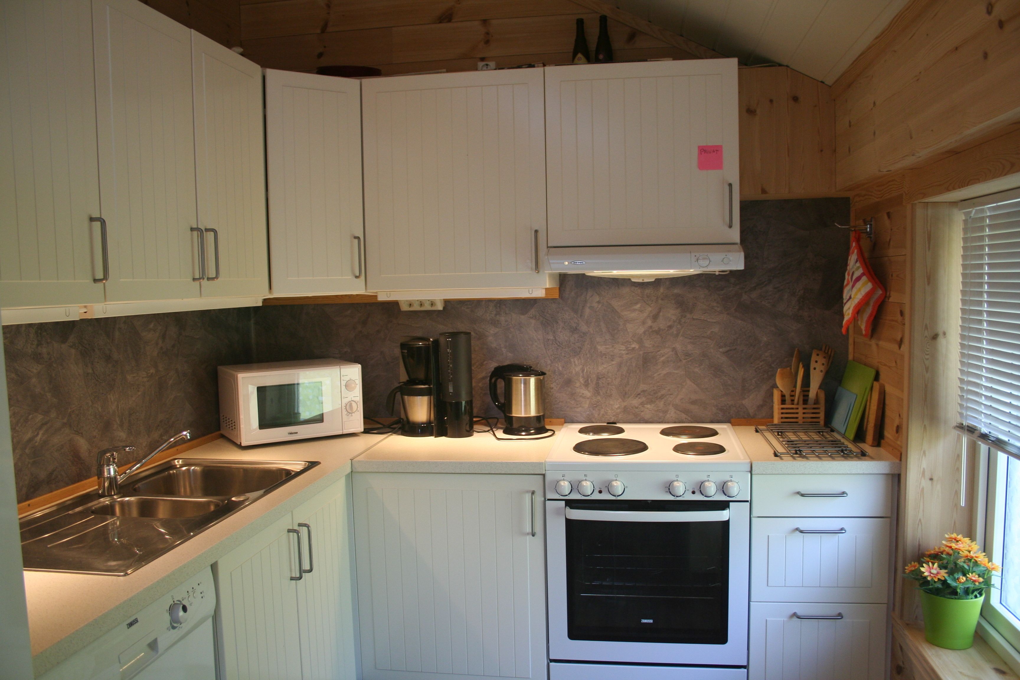 Fullt utstyrt kjøkken med komfyr, vask og kvite skap på Vågen Rom og Hytteutleige.