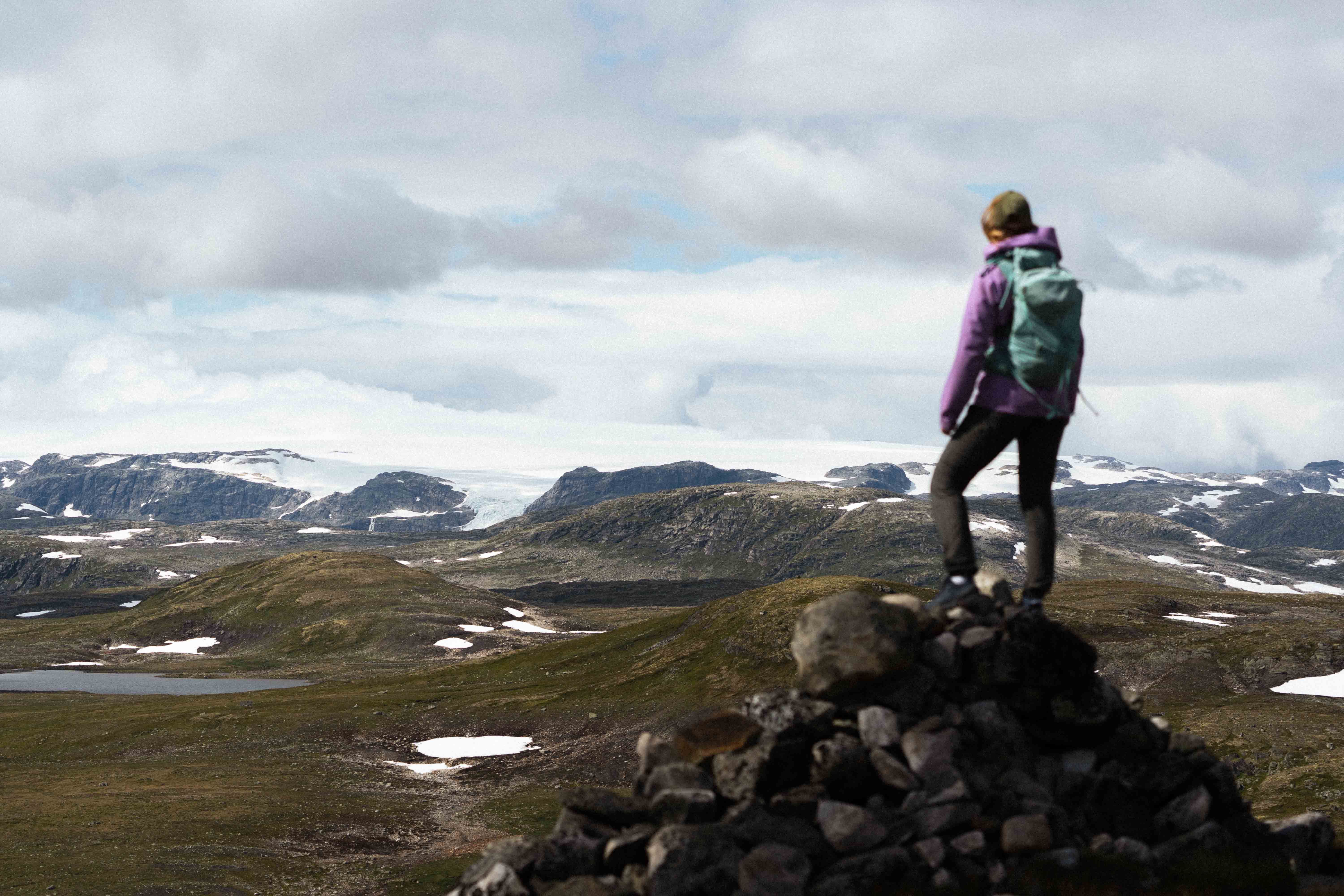 A woman standing on a mountain top gazing towards the Hardangerjøkulen glacier.