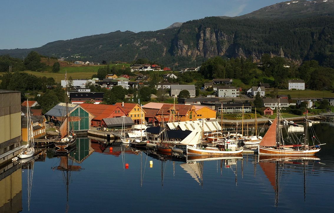 Overview of Hardanger Maritime Center with several sailboats and traditional buildings along the dock.