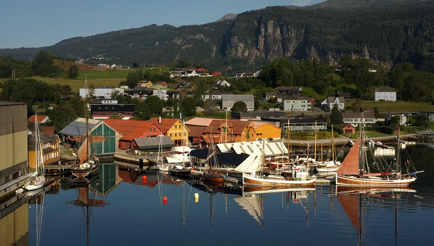 Overview of Hardanger Maritime Center with several sailboats and traditional buildings along the dock.
