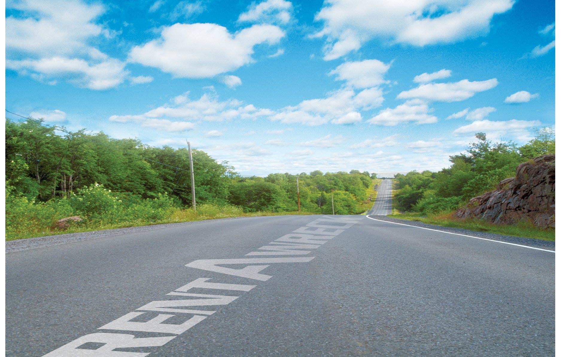 Vei med Rent-A-Wreck tekst. Grønne trær og blå himmel.