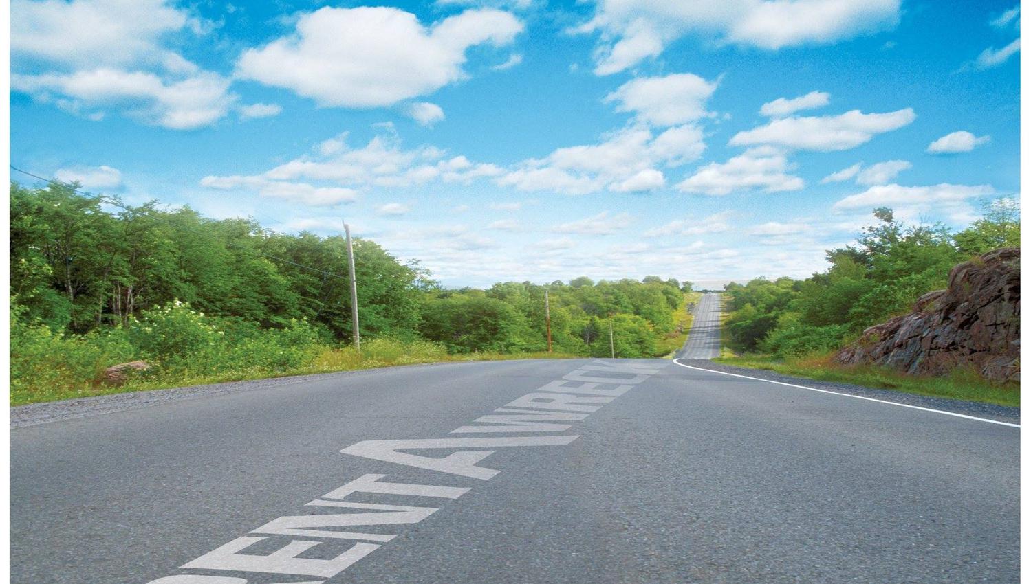 Vei med Rent-A-Wreck tekst. Grønne trær og blå himmel.