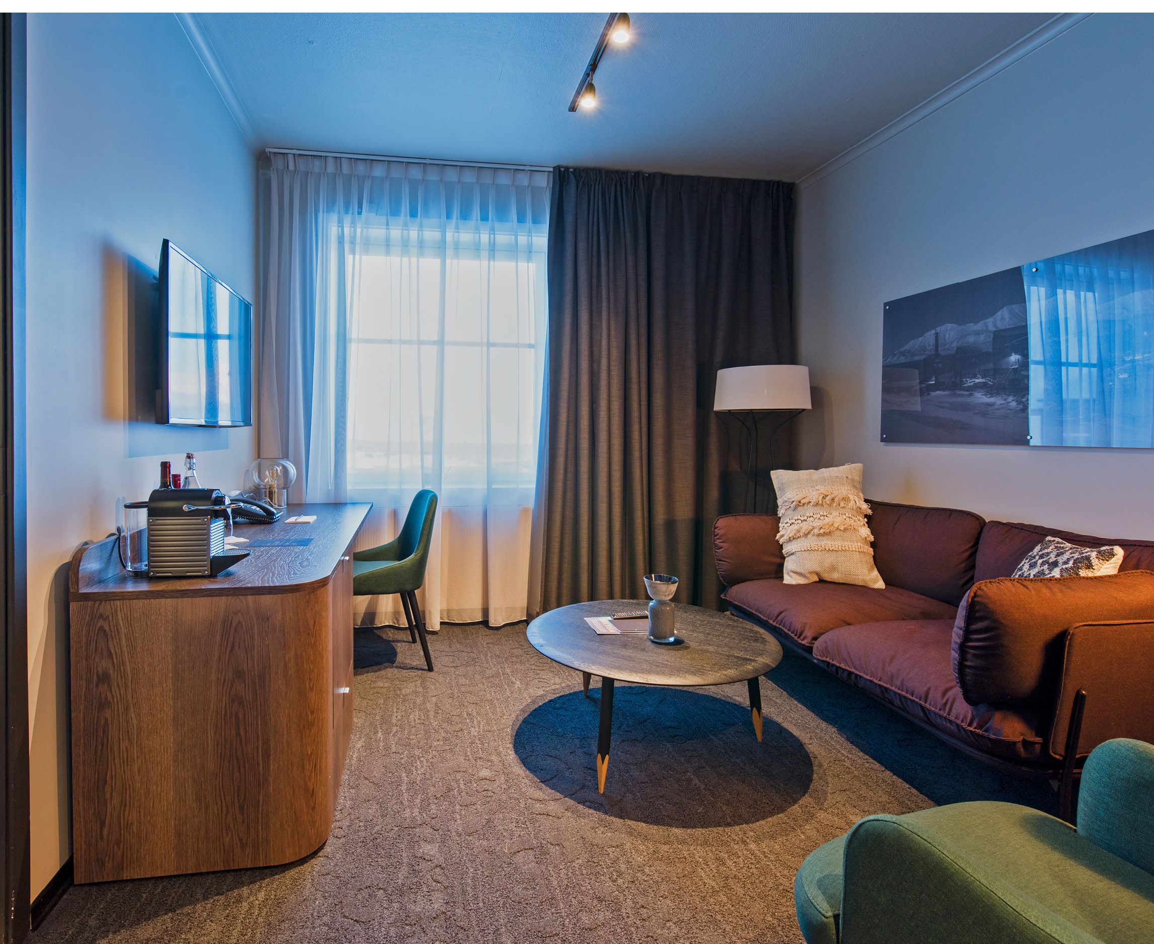 Et hotellrom med en sofa, kaffebord og arbeidspult