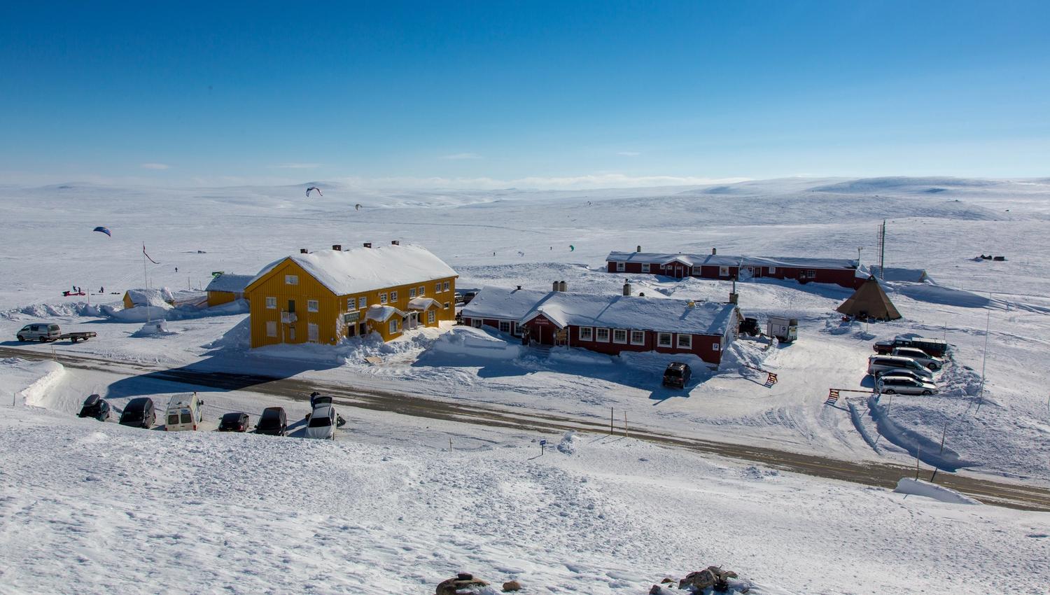 Den røde Dyranut Fjellstova og gule Dyranut Turisthytta i snølandskap.