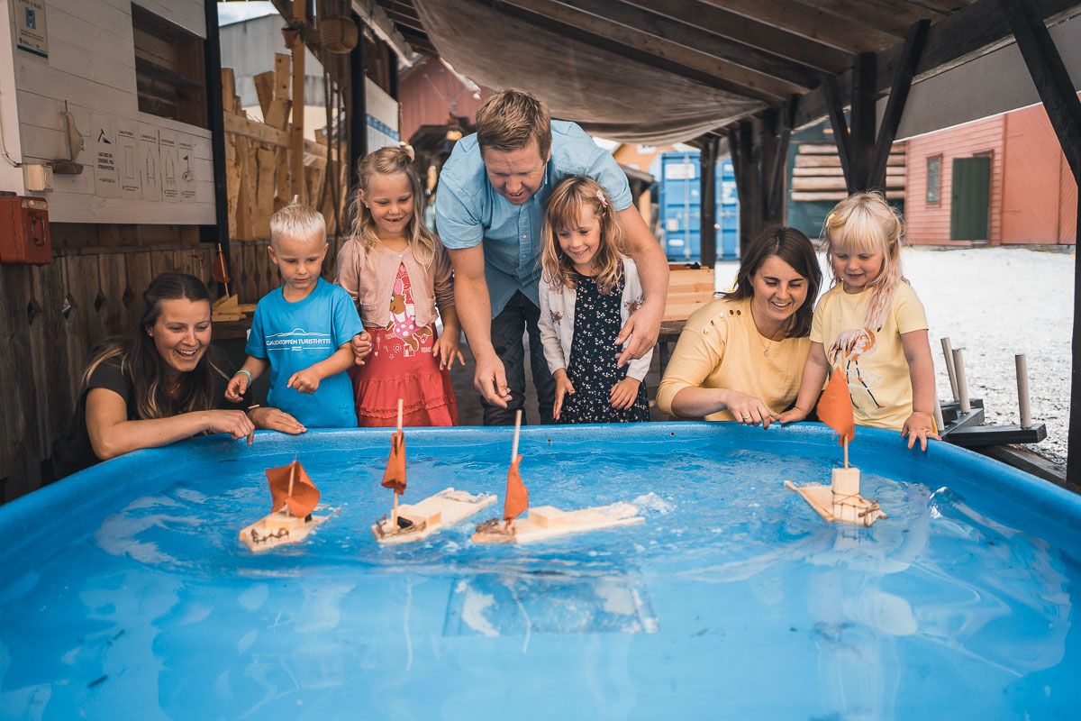 A family playing with small sailboats on water at Hardanger Maritime Center.