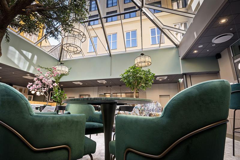 Restaurant interior with a glass ceiling and green armchairs.