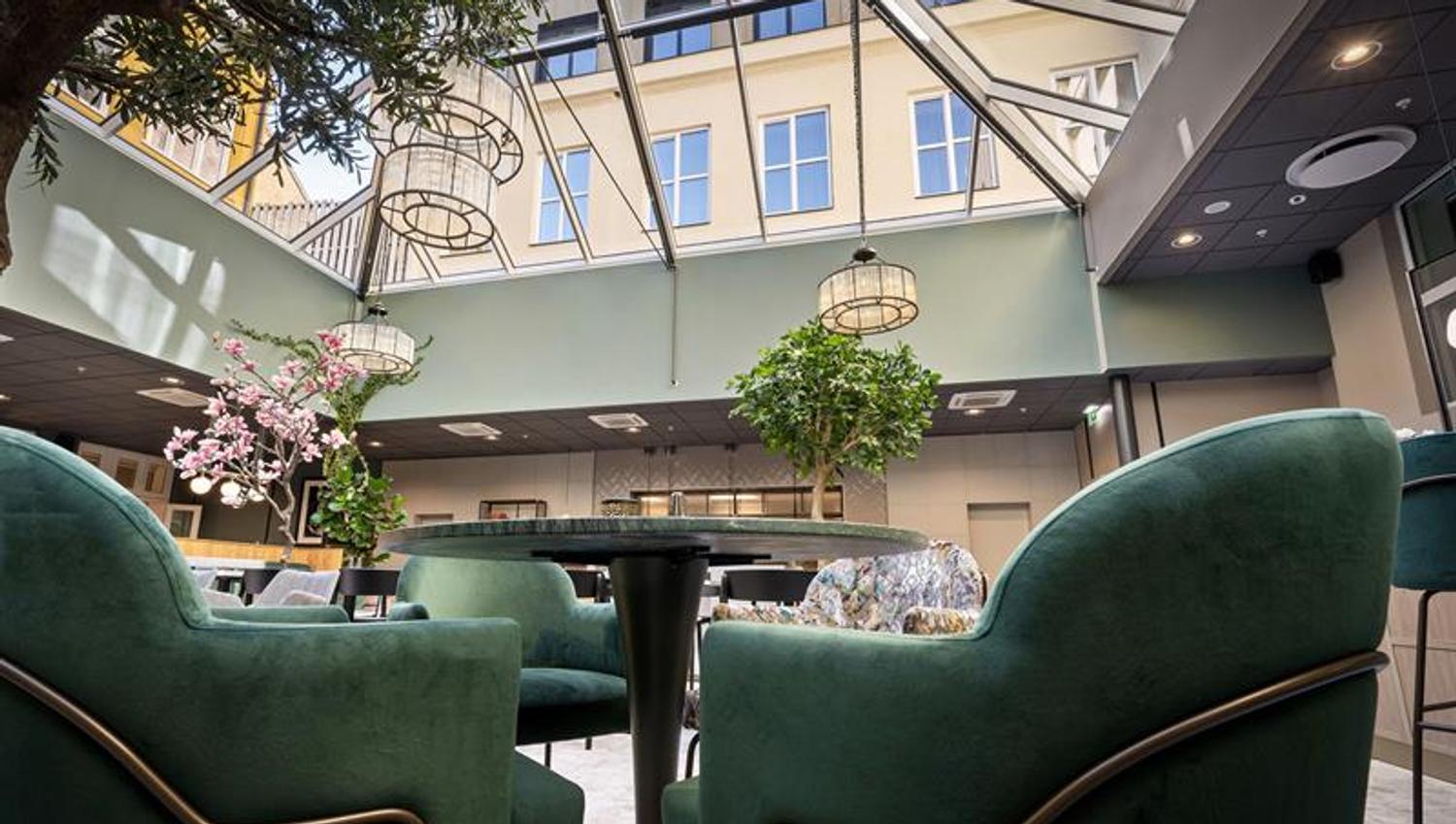 Restaurant interior with a glass ceiling and green armchairs.