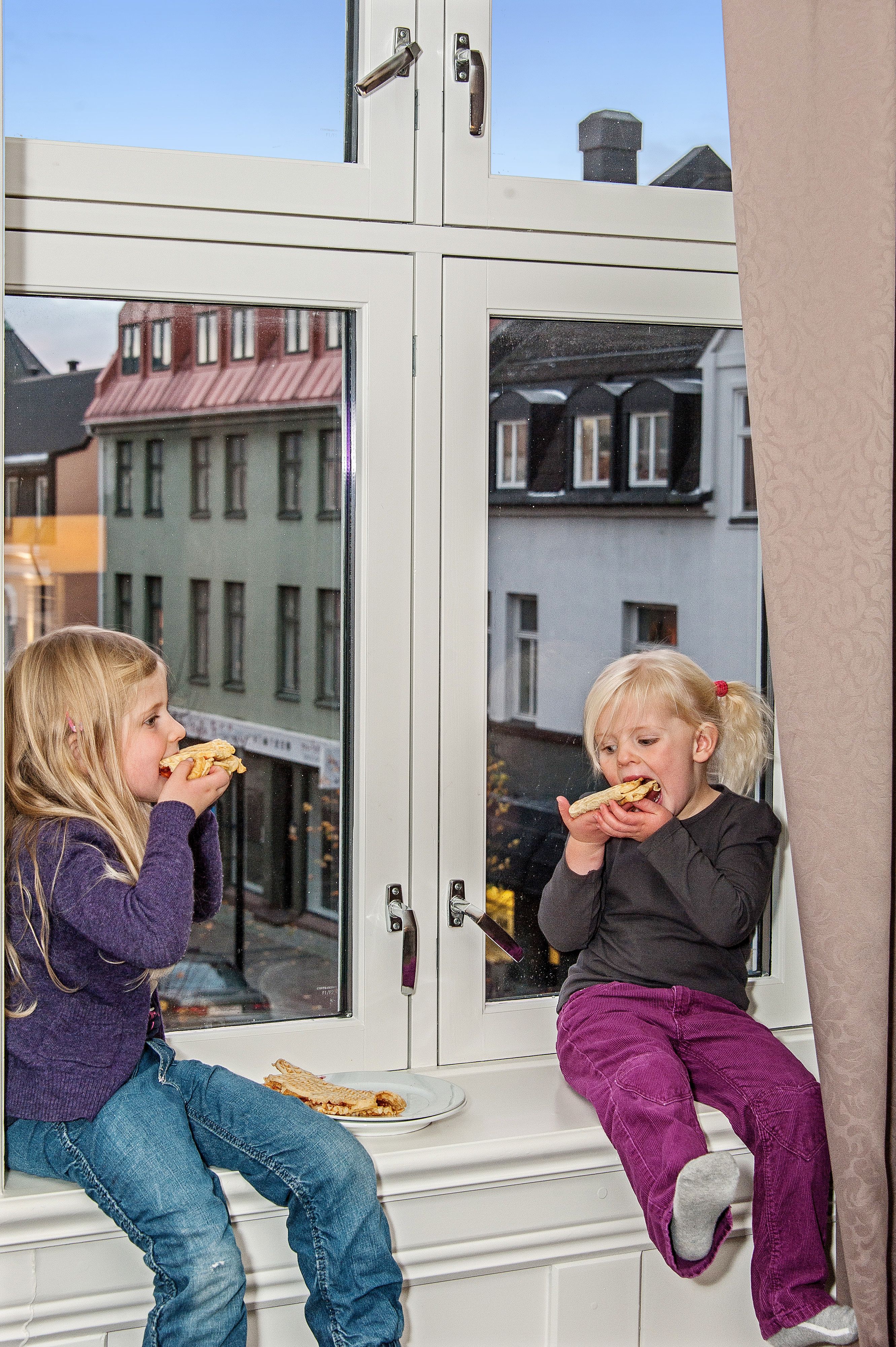 Children sit on the windowsill and eat food