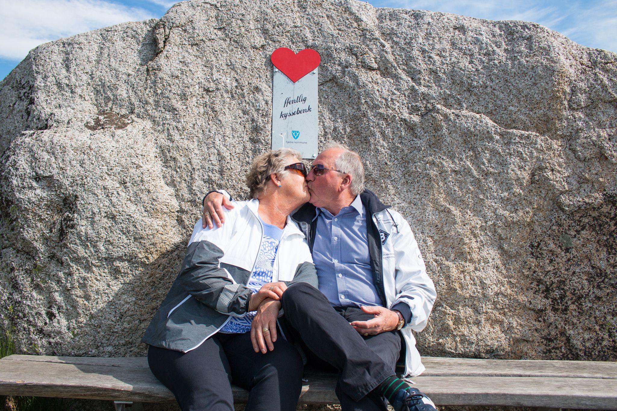 Two people kiss on a kissing bench at the End of the World