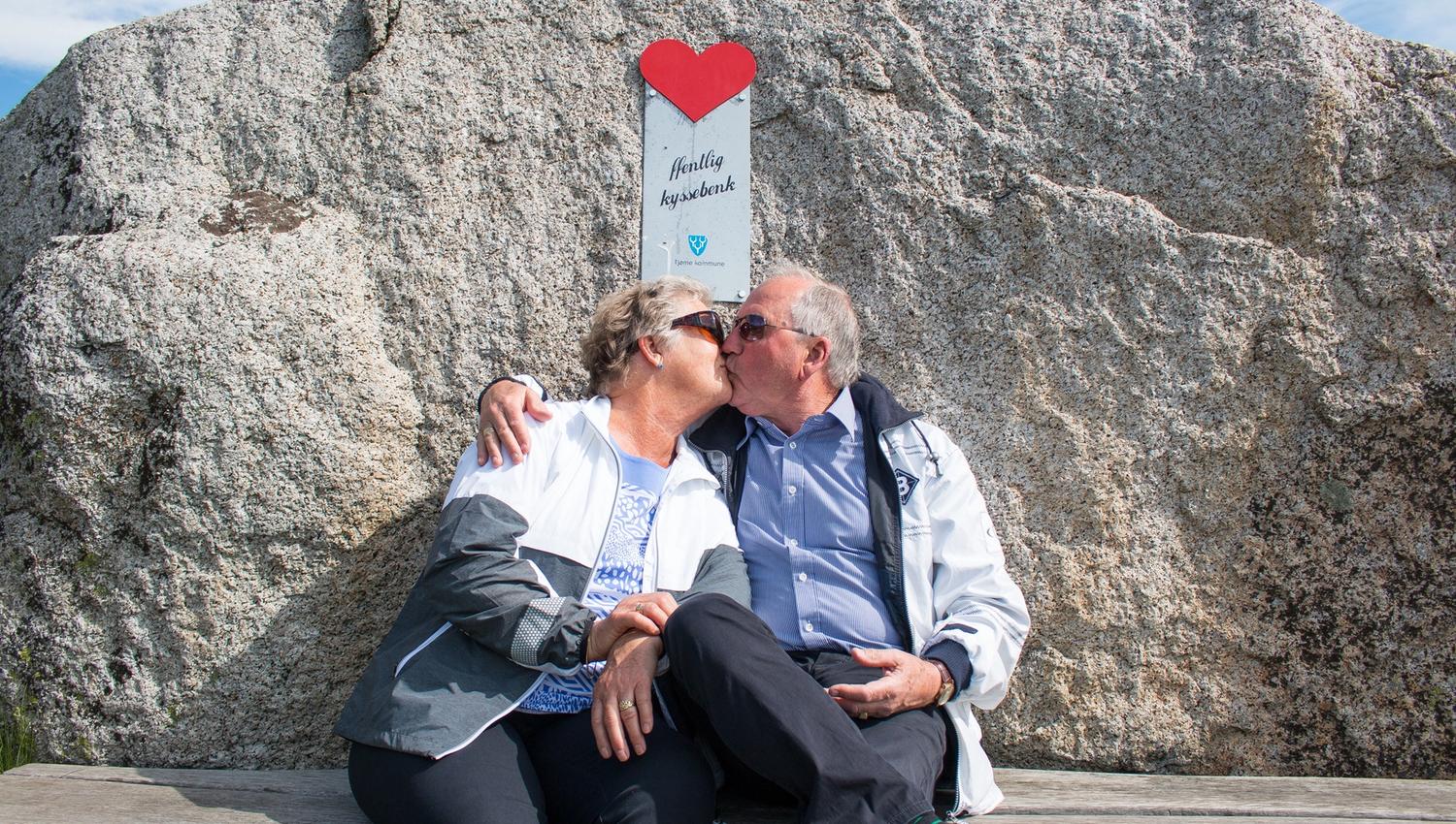 Two people kiss on a kissing bench at the End of the World