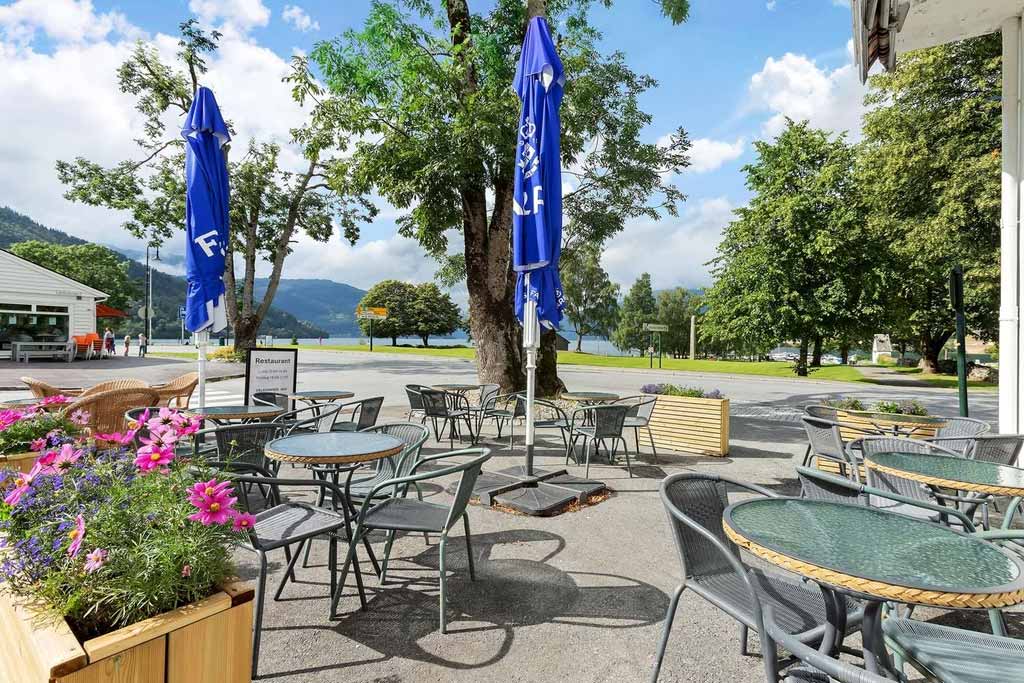 Uteområdet til Kinsarvik Fjordhotel, med sitjeplassar og flott utsikt mot fjord og fjell.