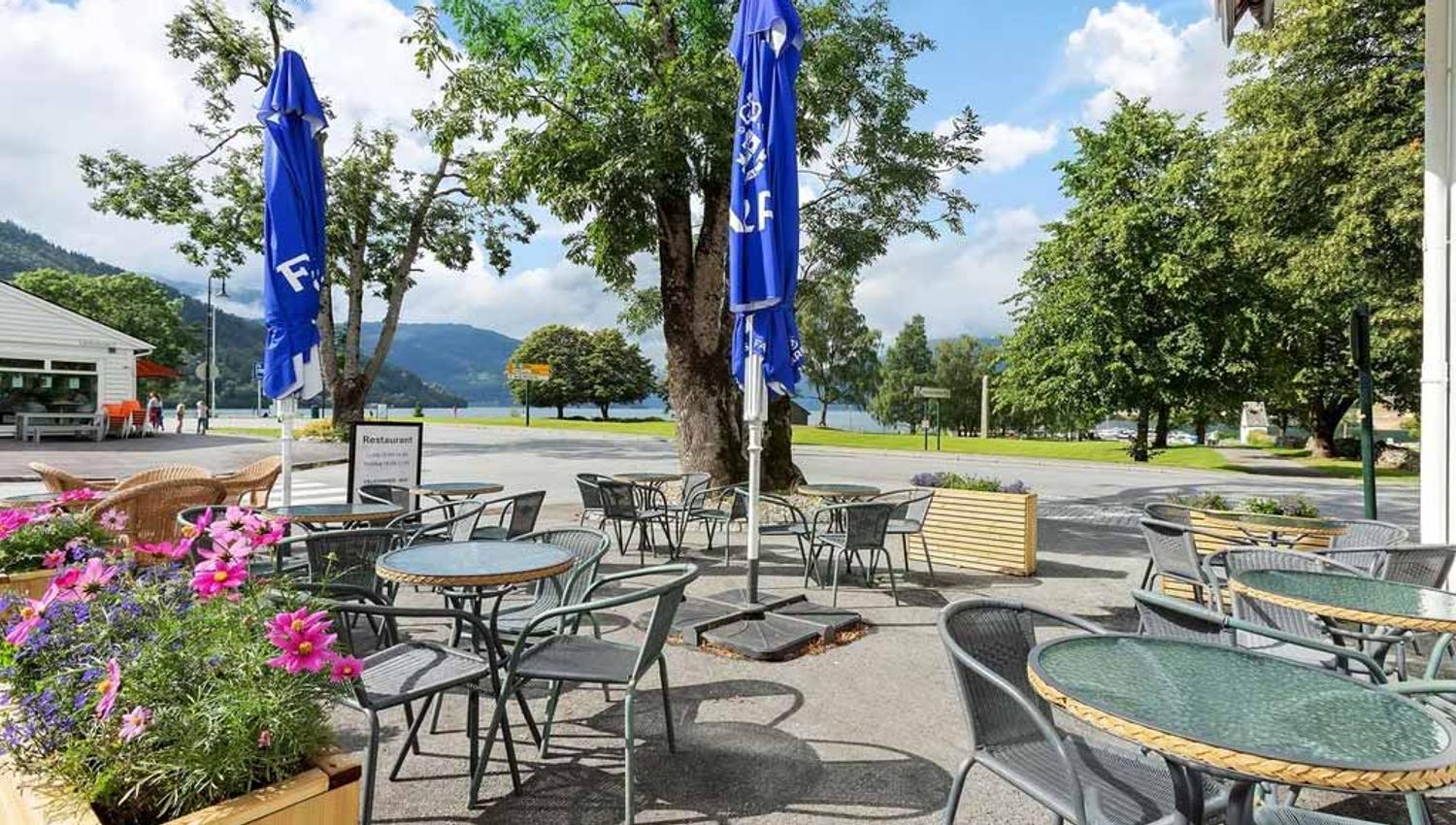 Uteområdet til Kinsarvik Fjordhotel, med sitjeplassar og flott utsikt mot fjord og fjell.