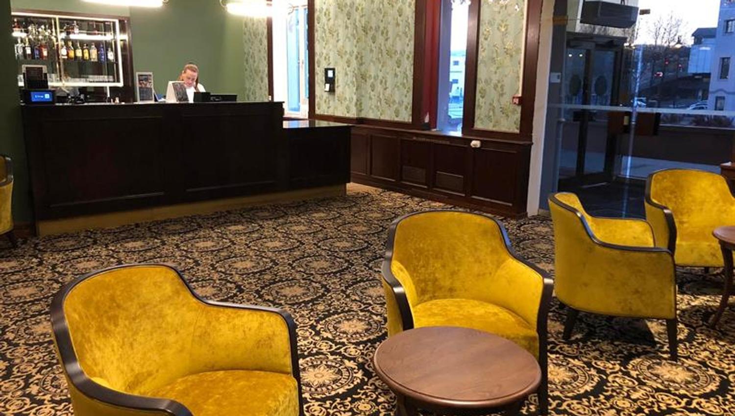 Gule stoler, mønstrete gulvteppe og resepsjonsdisk