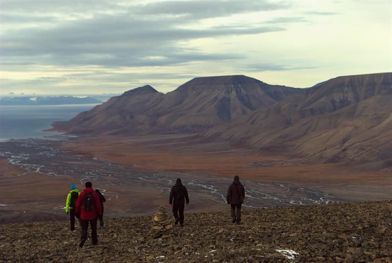Personer som går ned fra et fjell med elver og fjell i bakgrunnen