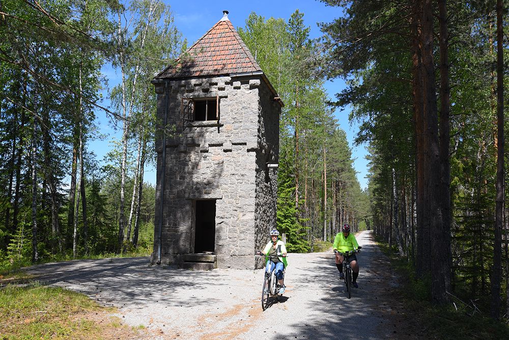2 syklister sykler forbi et tårn på sykkelveien "gamle Treungenbanen"