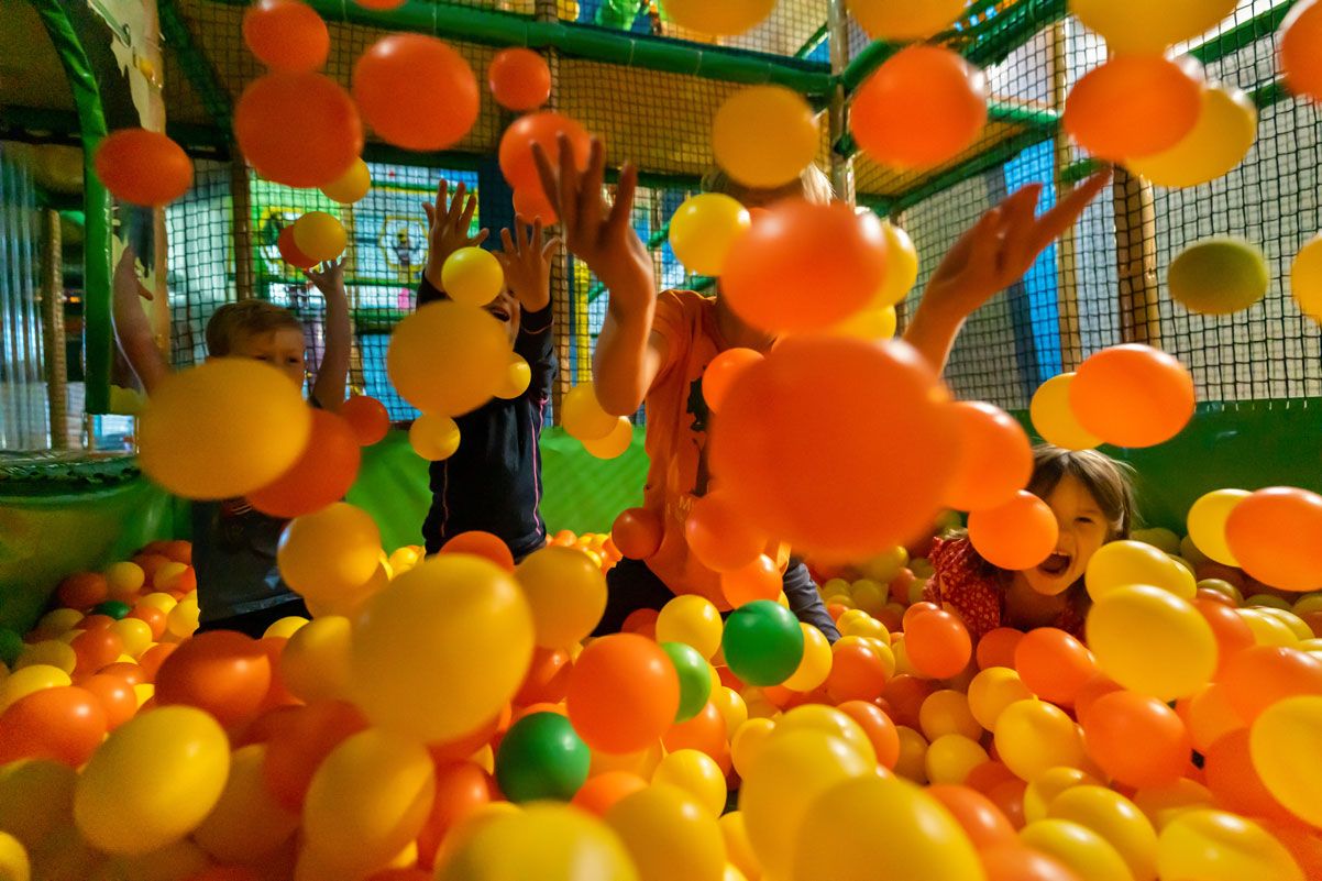 Children playing and throwing colourful balls in the ball pit at Mikkelparken in Kinsarvik.