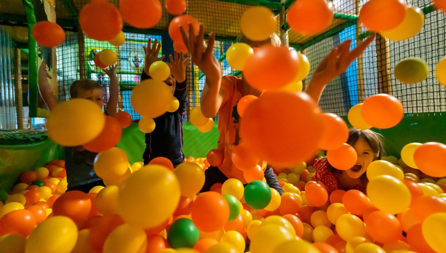 Children playing and throwing colourful balls in the ball pit at Mikkelparken in Kinsarvik.