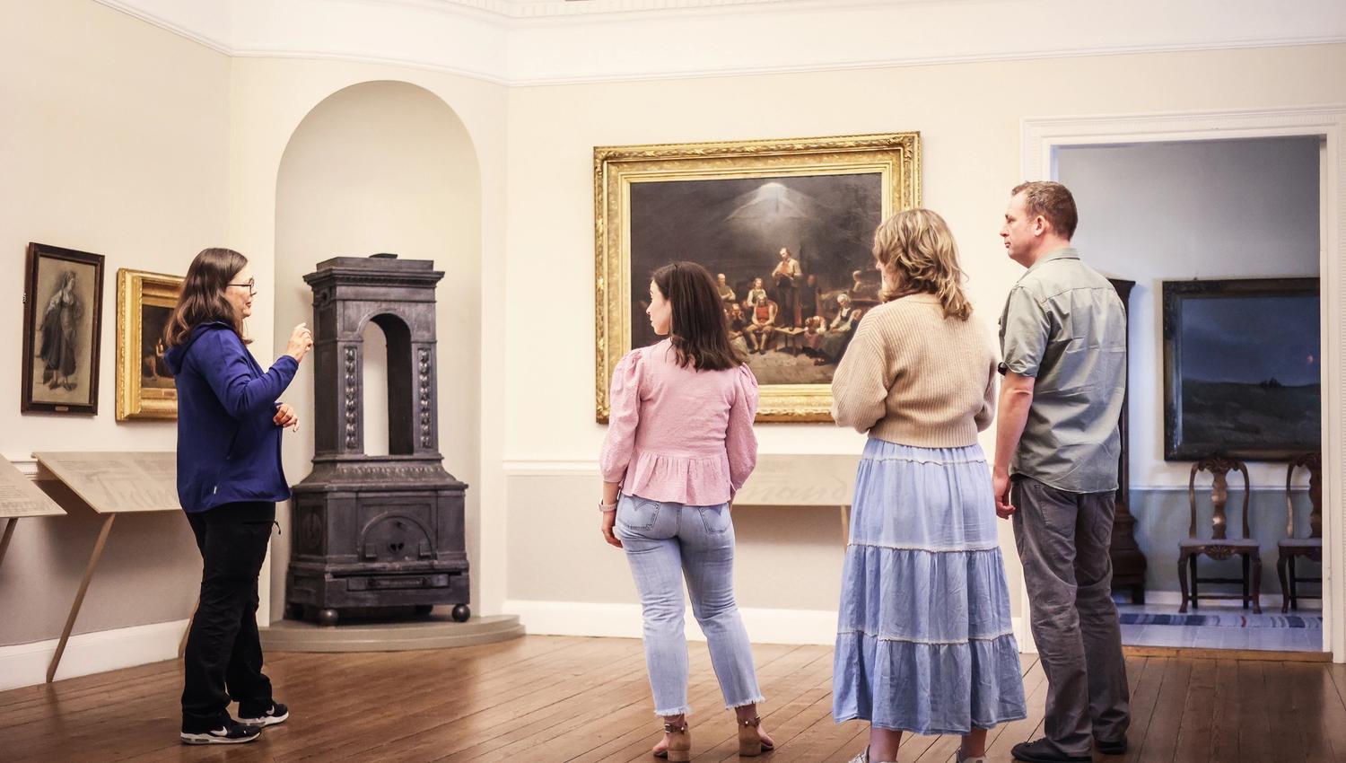 Fire personer inne på museet ser på det store maleriet «Haugianerne» på Mandal museum, der Adolph Tidemand skildrer lekpredikanten Hans Nielsen Hauges følgere.
