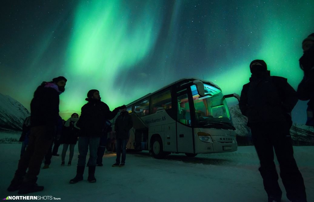 En gruppe gjester som står foran bussen