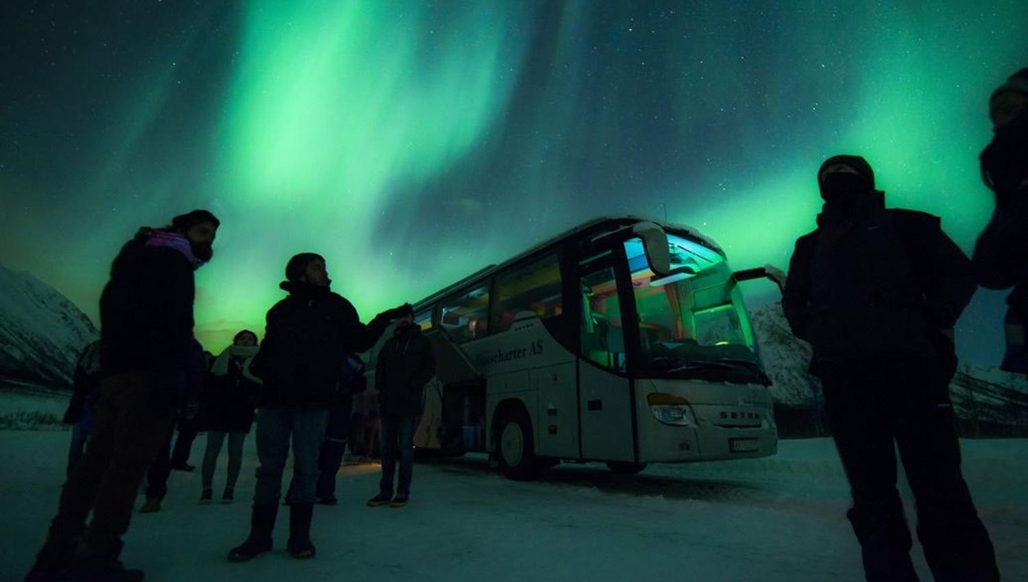 En gruppe gjester som står foran bussen