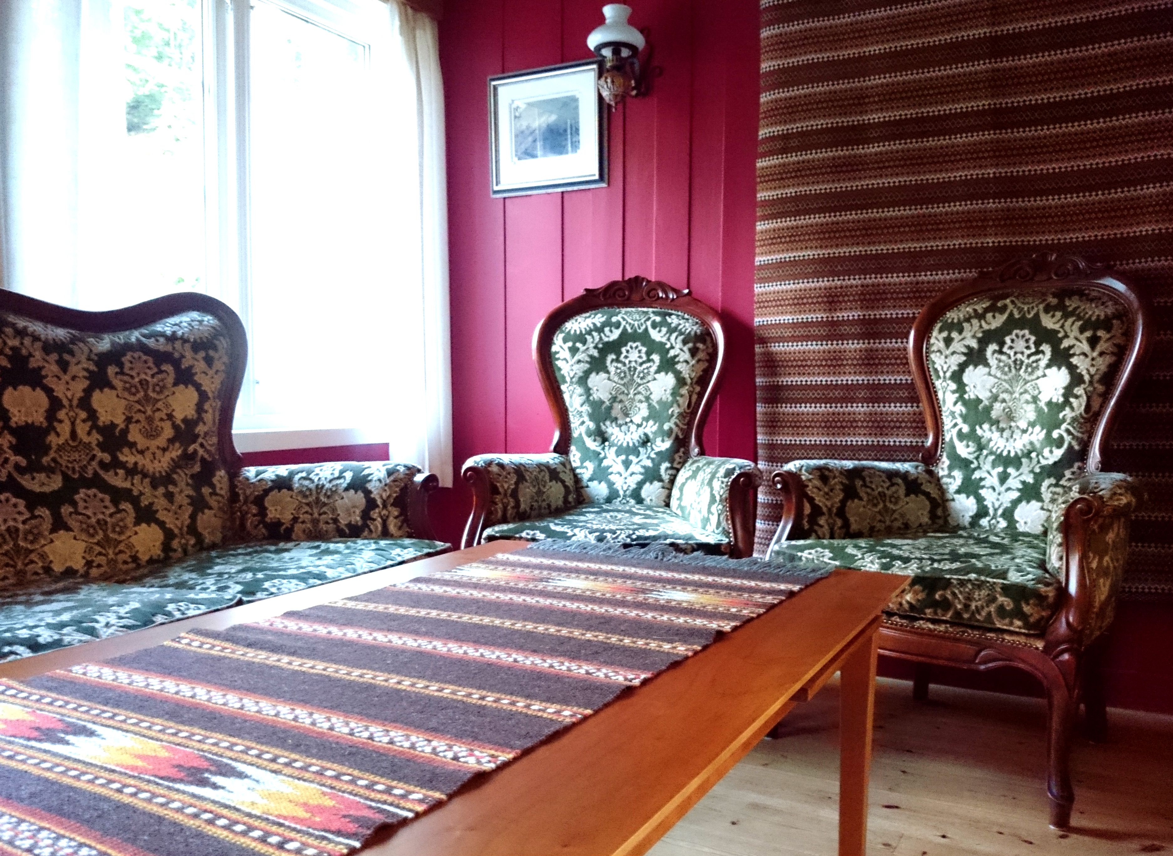 Hyggjeleg sittegruppe med antikke stolar og sofa i tradisjonell stil på Ullensvang Gjesteheim.